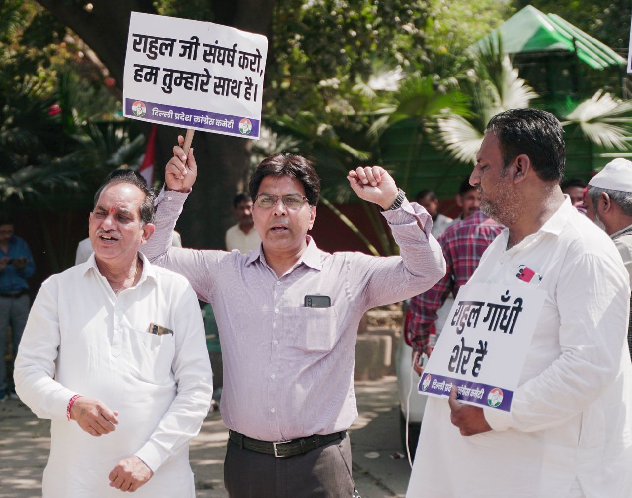 A group of men holding signs in an outdoor political protest.