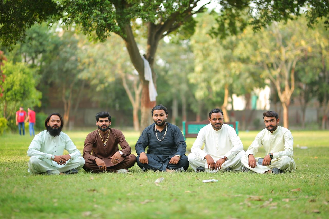 Home Group of men in traditional attire sitting in a park in Lahore, Pakistan.